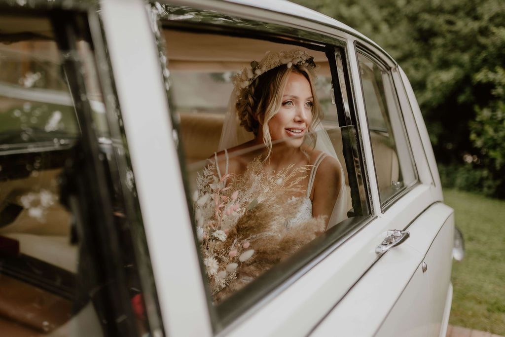 A bride sits in a car with a vintage flower bouquet from Hidden Botanics.