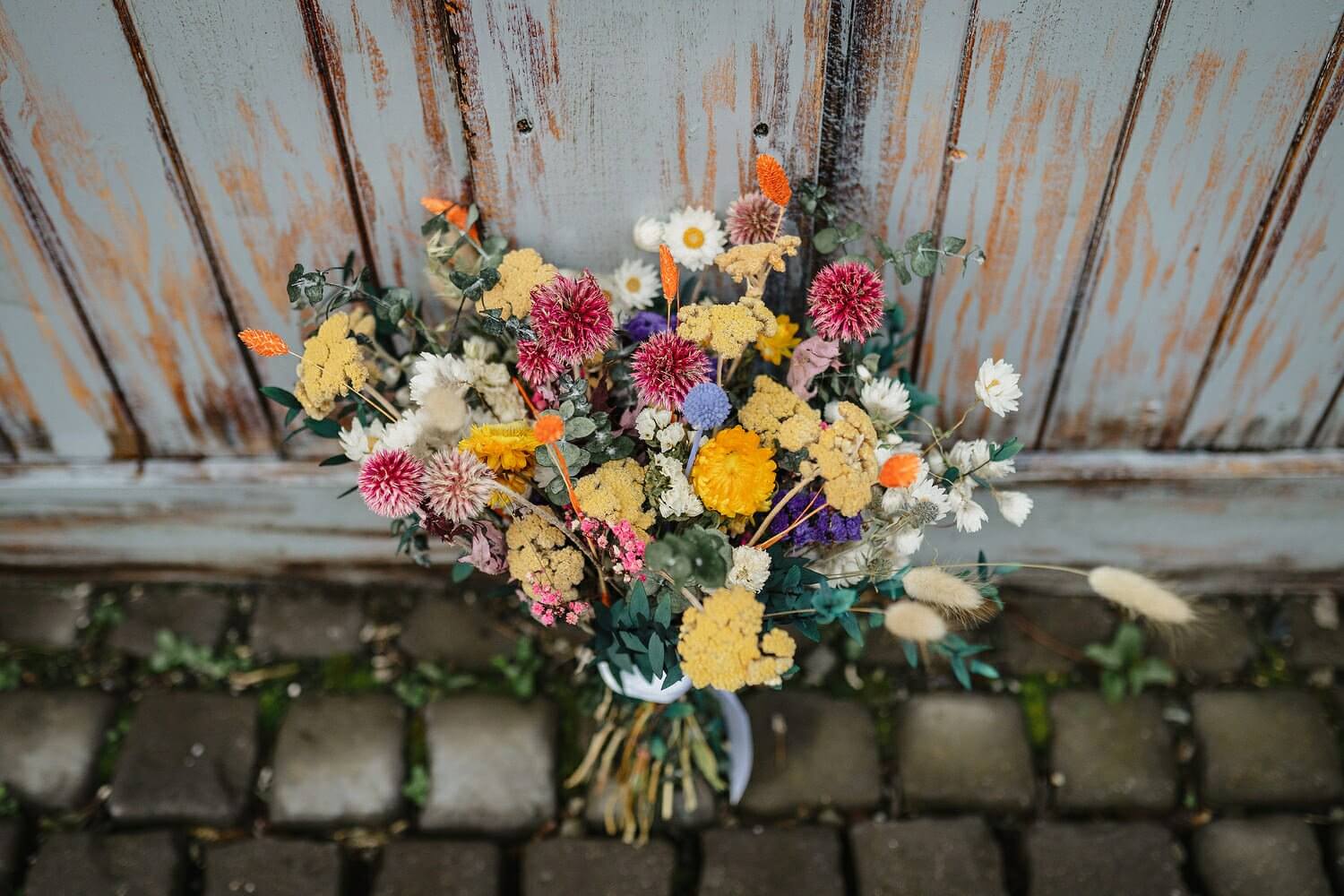 A colorful bunch of dried wildflowers sitting against a fence.