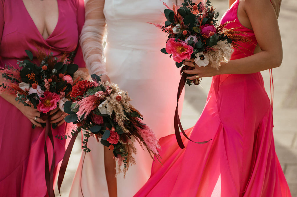 Bride and bridesmaids in pink dresses holding dried flower bouquets from Hidden Botanics.